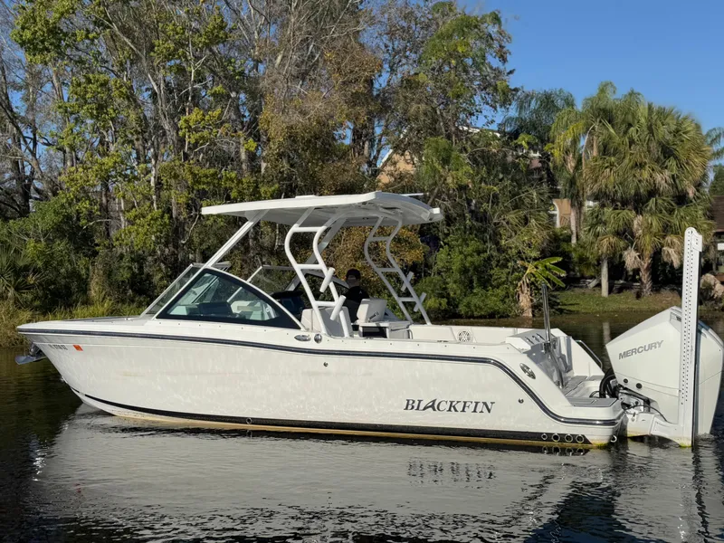 Slide: The Image of 2021 Blackfin 252DC boat on calm water, surrounded by lush trees. - 28