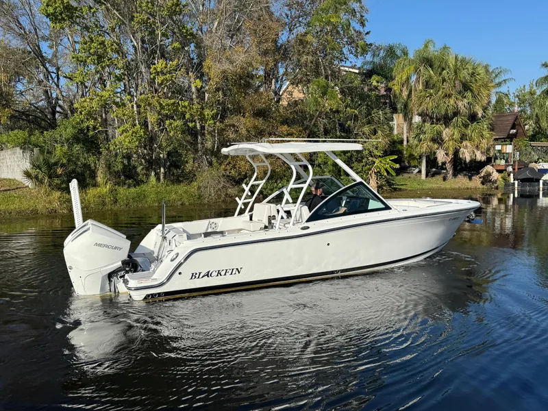 Slide: The Image of 2021 Blackfin 252DC boat on a calm river, surrounded by lush greenery. - 3