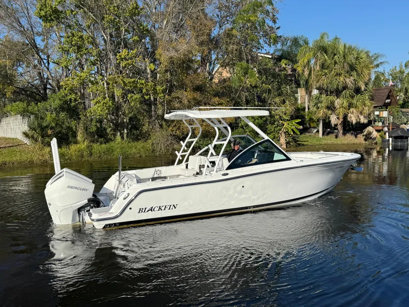 Slide: The Image of 2021 Blackfin 252DC boat cruising on a calm river with lush greenery. - 4