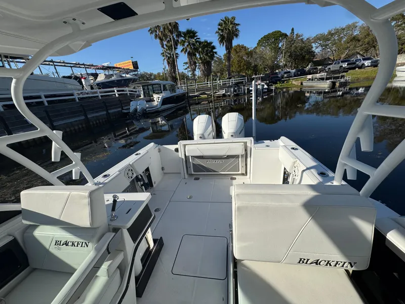 Slide: The Image of 2021 Blackfin 252DC boat interior with seating, docked near palm trees. - 44