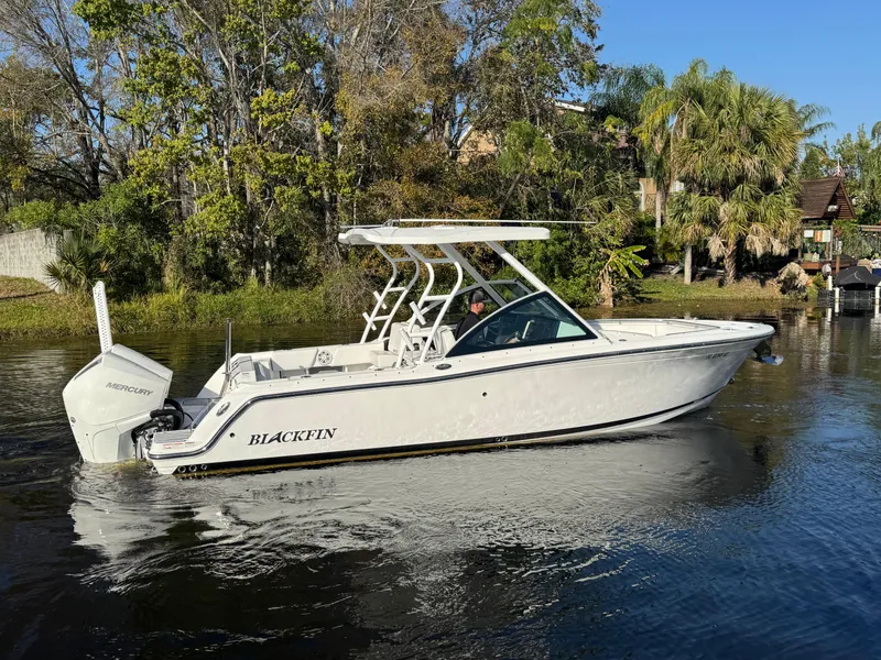 Slide: The Image of 2021 Blackfin 252DC boat cruising on a calm river with lush greenery. - 5