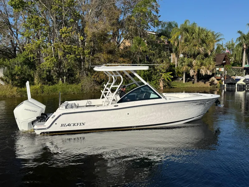 Slide: The Image of 2021 Blackfin 252DC boat on calm water, surrounded by lush greenery. - 6