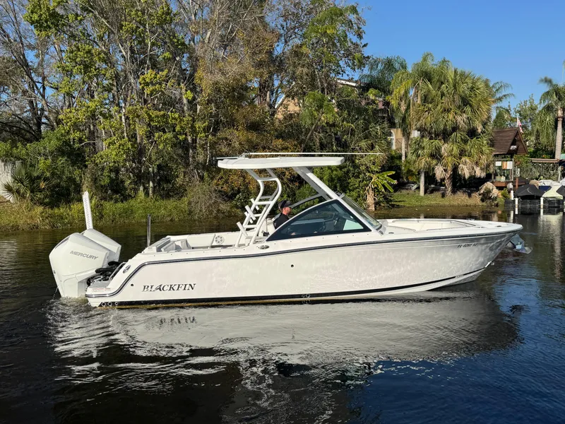 Slide: The Image of 2021 Blackfin 252DC boat on a calm river, surrounded by lush greenery. - 7
