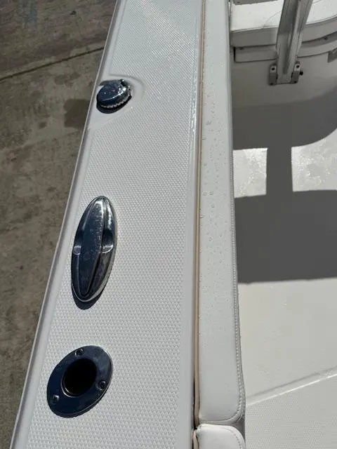 Slide: The Image of 2025 Robalo 266 Cayman boat interior with sleek white seating and stainless steel fixtures. - 11