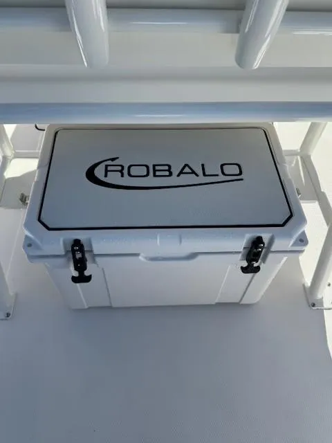 Slide: The Image of 2025 Robalo 266 Cayman cooler, white with logo, secured on boat deck. - 14