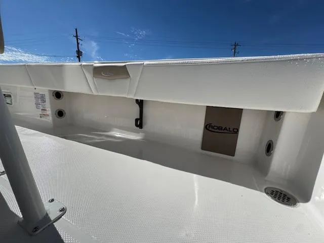 Slide: The Image of 2025 Robalo 266 Cayman boat deck with storage compartment under clear blue sky. - 17