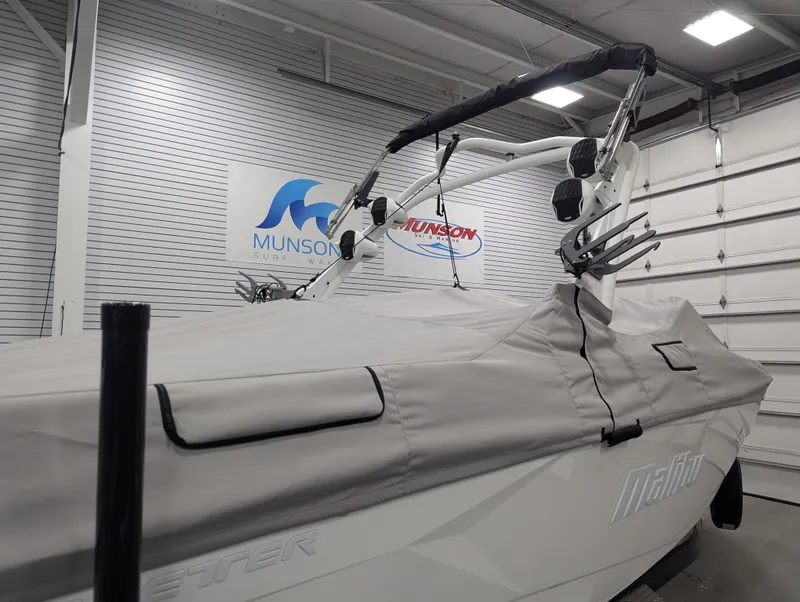 Slide: The Image of 2025 Malibu Wakesetter 23 LSV boat covered in a garage, Munson Marine sign visible. - 24