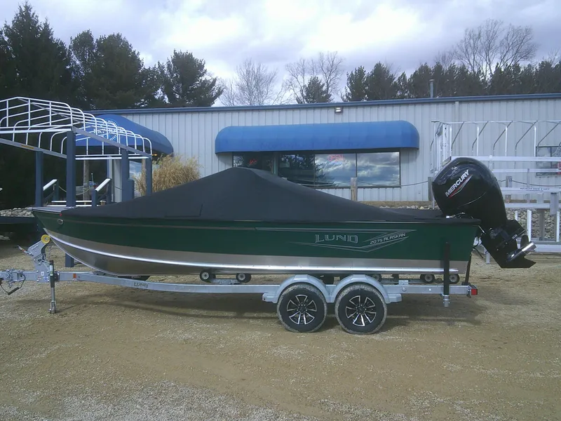 Slide: The Image of 2025 Lund 2075 Alaskan Sport boat on trailer, covered, with outboard motor, parked outdoors. - 19