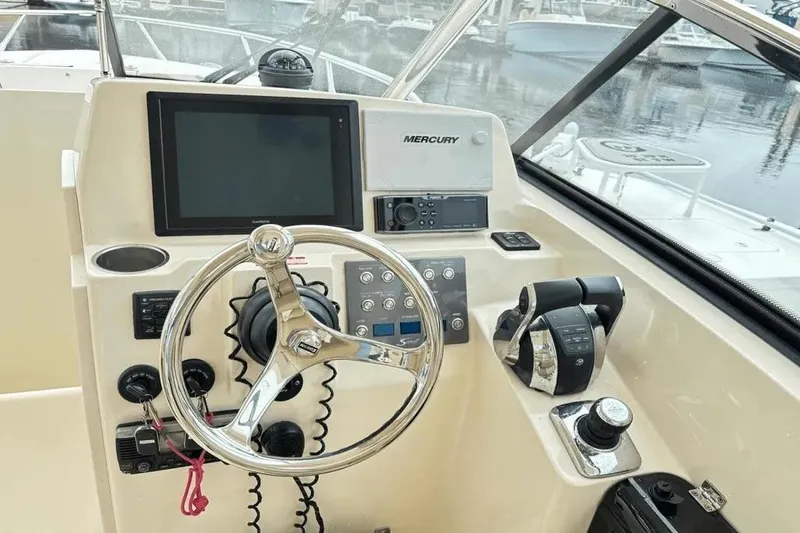 Slide: The Image of Control panel of a 2015 Scout 275 Dorado boat with steering wheel and navigation equipment. - 14