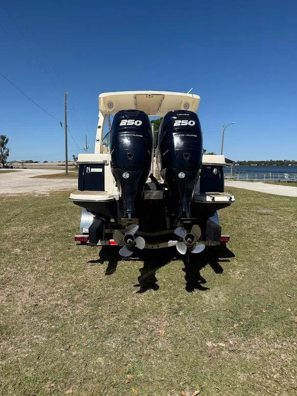 Slide: The Image of 2015 Scout 275 Dorado boat with twin 250 horsepower engines, parked on grass near water. - 28