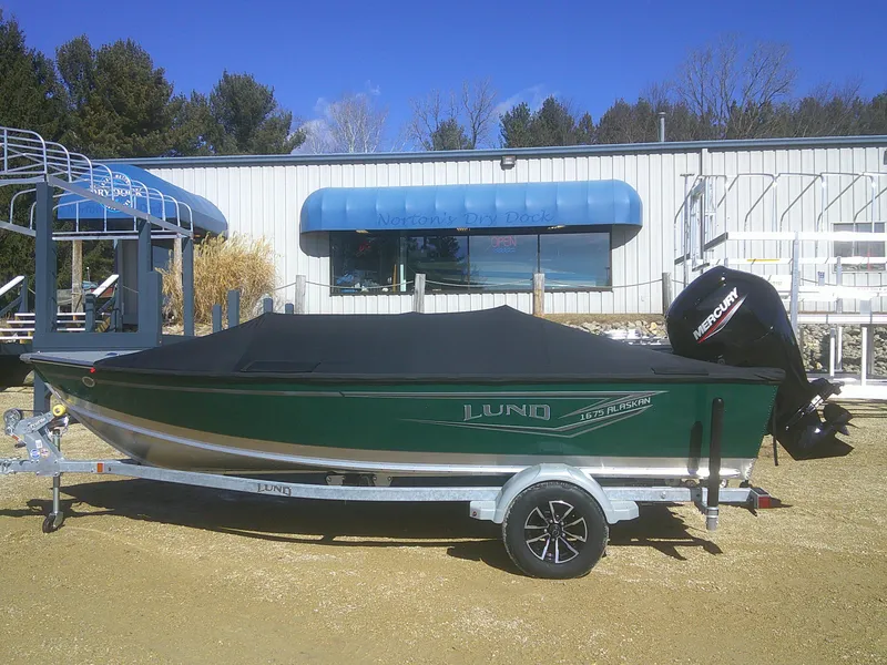 Slide: The Image of 2025 Lund 1675 Alaskan SS boat with cover on trailer, parked outdoors. - 19