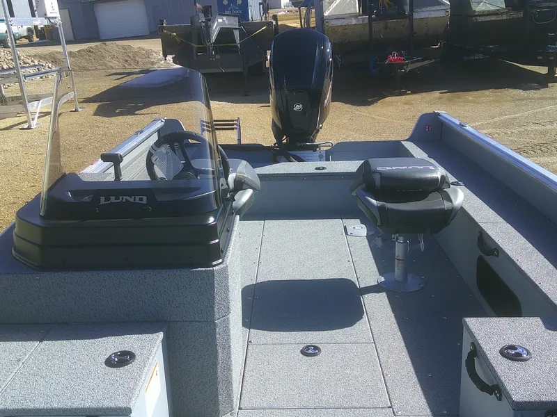 Slide: The Image of 2025 Lund 1675 Alaskan SS boat interior with seating and motor, parked outdoors. - 8