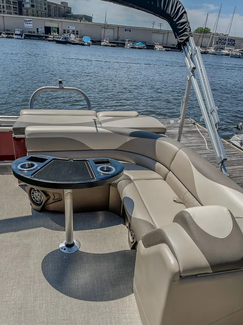 Slide: The Image of 2021 Avalon LSZ 2485 CR pontoon boat with beige seating and table, docked by the water. - 9