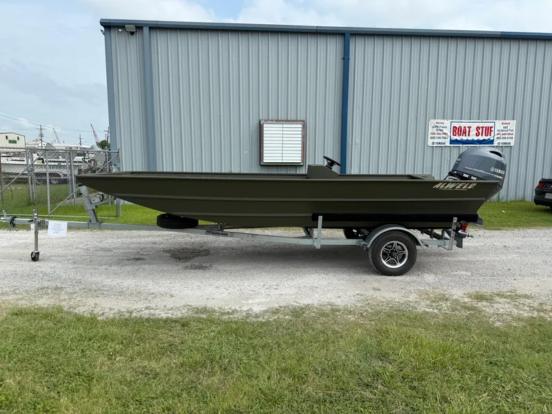 The Image of 2025 Alweld 1860 SC FLAT boat on trailer, parked outside a metal building. - 0