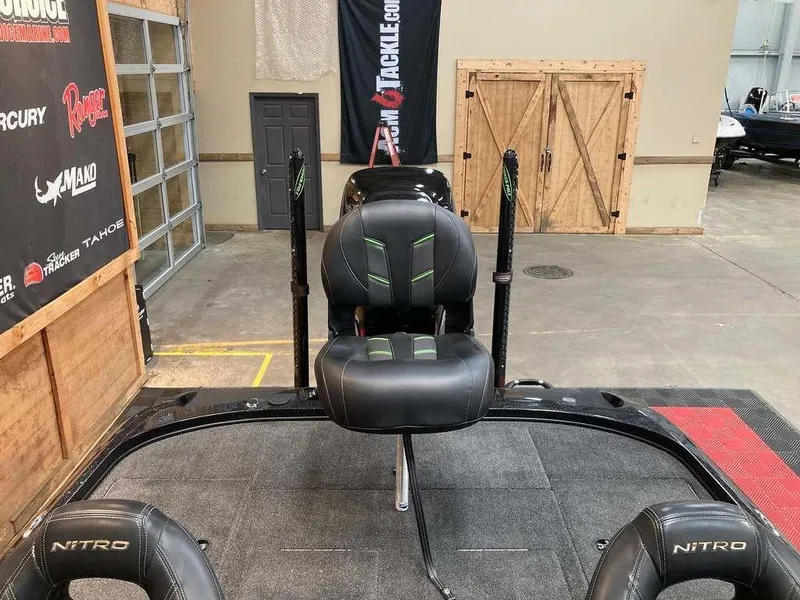 Slide: The Image of 2017 Nitro Z19 boat interior with black seats and fishing rod holders in a showroom. - 11