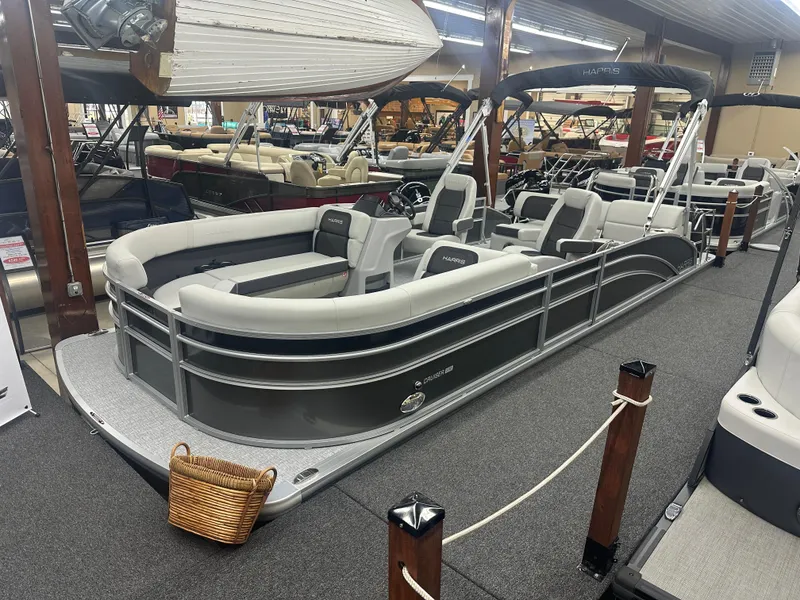 The Image of 2025 Harris Cruiser 230 pontoon boat displayed in a showroom, featuring sleek design and spacious seating. - 1