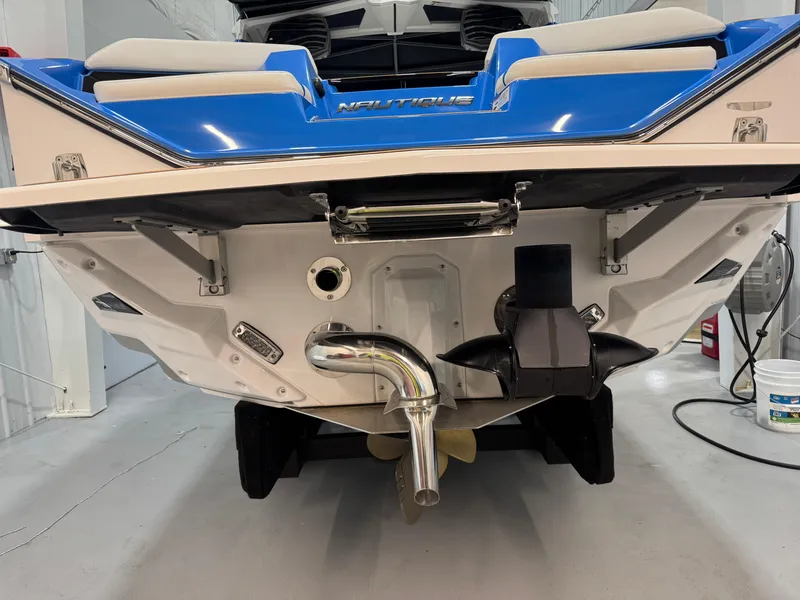 Slide: The Image of 2025 Nautique Super Air Nautique S23 boat rear view in a garage setting. - 11