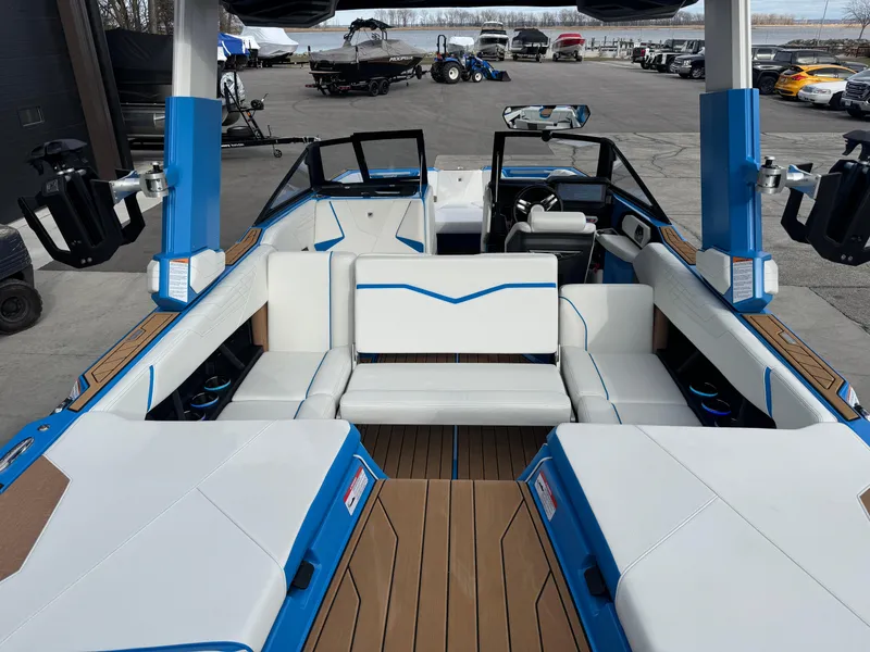 Slide: The Image of 2025 Nautique Super Air Nautique S23 boat interior with blue and white seating, docked outdoors. - 16