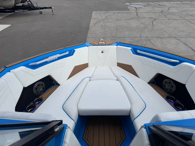 Slide: The Image of 2025 Nautique Super Air Nautique S23 boat interior with white and blue seating. - 18