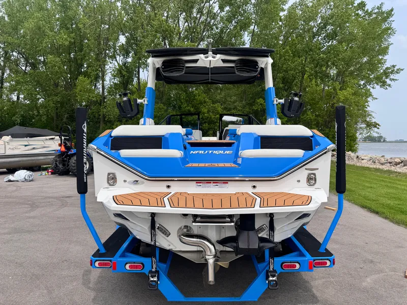 Slide: The Image of 2025 Nautique Super Air Nautique S23 boat on trailer, rear view, blue and white design. - 4
