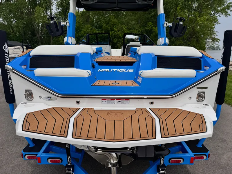 Slide: The Image of 2025 Nautique Super Air Nautique S23 boat, blue and white, rear view with teak deck. - 5