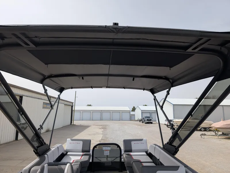 Slide: The Image of 2025 Manitou Cruise boat with canopy, parked in a storage facility. - 28