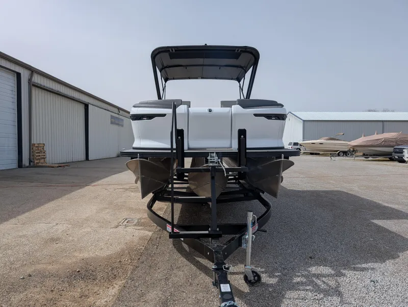 Slide: The Image of 2025 Manitou Cruise boat on trailer, parked outdoors near storage buildings. - 31