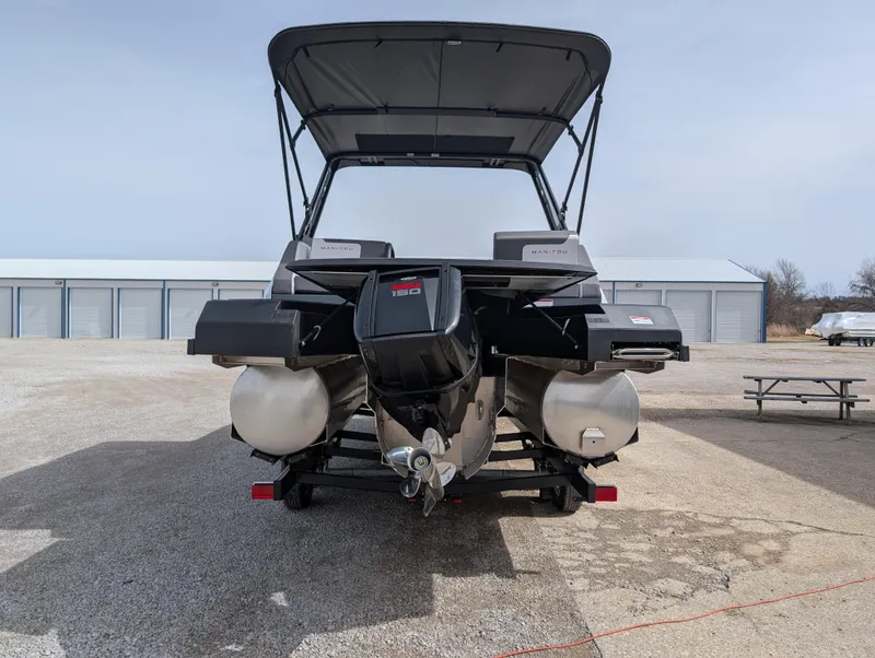 Slide: The Image of 2025 Manitou Cruise pontoon boat with outboard motor, parked on a concrete surface. - 35