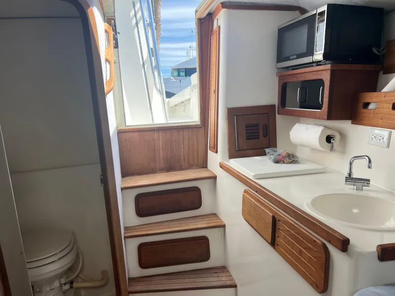 Slide: The Image of 1999 Contender 35 Center Console interior with cuddy, featuring a sink, microwave, and toilet. - 42