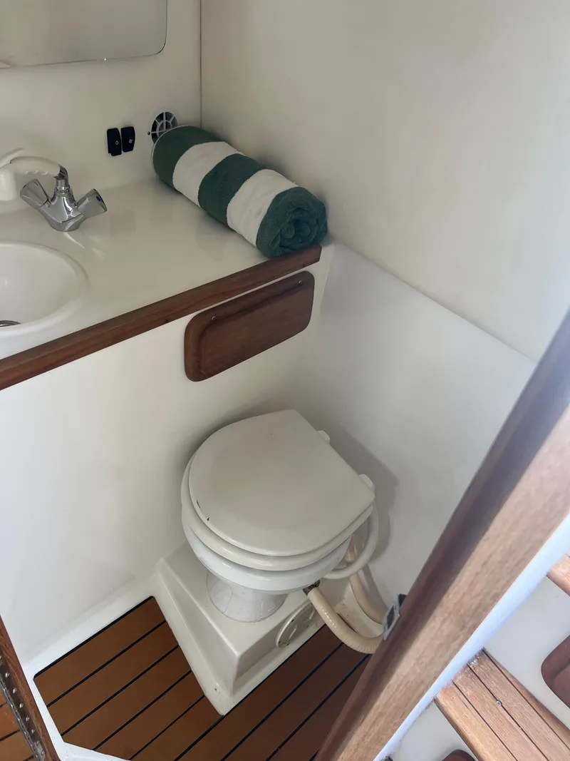 Slide: The Image of 1999 Contender 35 Center Console boat bathroom with toilet, sink, and wooden flooring. - 44