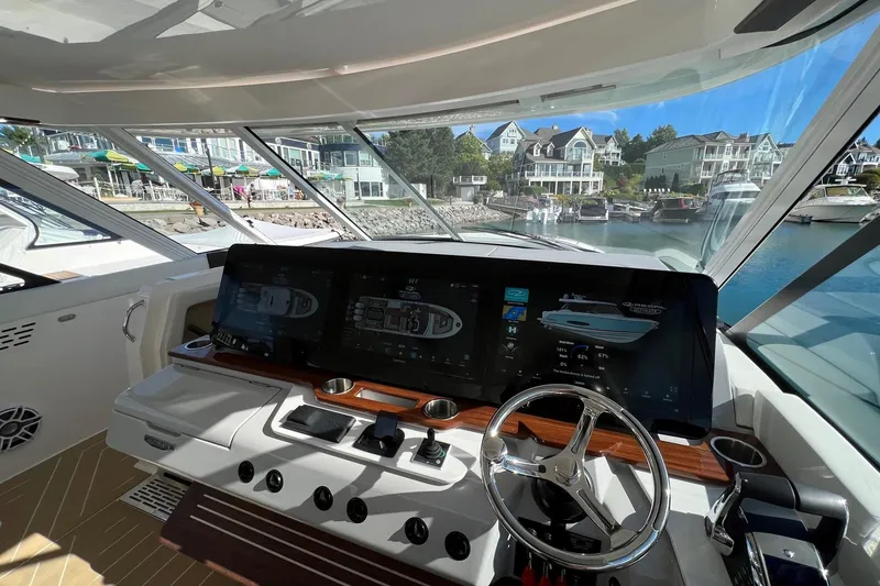 Slide: The Image of Helm of 2026 Regal LX43 yacht with advanced navigation screens, docked in a scenic marina. - 15