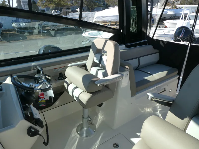 Slide: The Image of 2025 Boston Whaler 330 Vantage interior with helm seat and dashboard controls. - 10