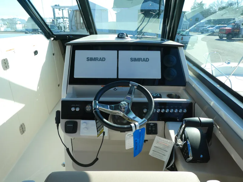 Slide: The Image of 2025 Boston Whaler 330 Vantage helm with dual Simrad displays and steering wheel. - 11