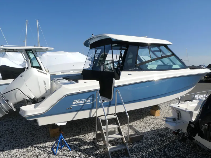 Slide: The Image of 2025 Boston Whaler 330 Vantage boat displayed on gravel with ladder access. - 4