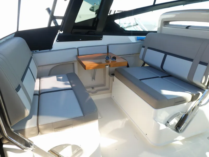 Slide: The Image of Interior seating of 2025 Boston Whaler 330 Vantage boat with table and sunglasses. - 7