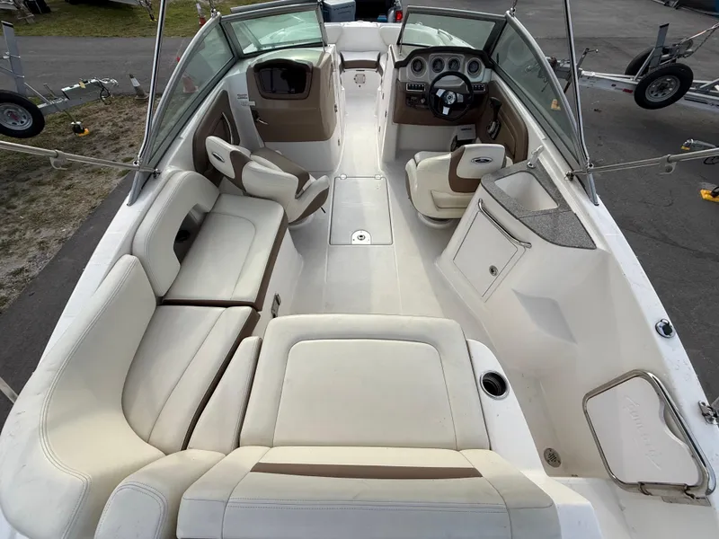 Slide: The Image of 2015 Chaparral Sunesta 224 boat interior with beige seating and steering console. - 18