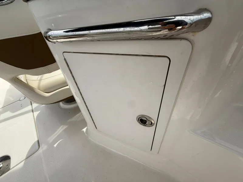 Slide: The Image of 2015 Chaparral Sunesta 224 boat storage compartment with chrome handle and white finish. - 31