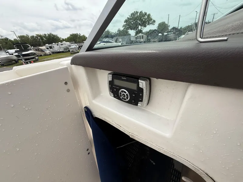 Slide: The Image of 2015 Chaparral Sunesta 224 boat interior with control panel, wet surfaces, and outdoor view. - 48