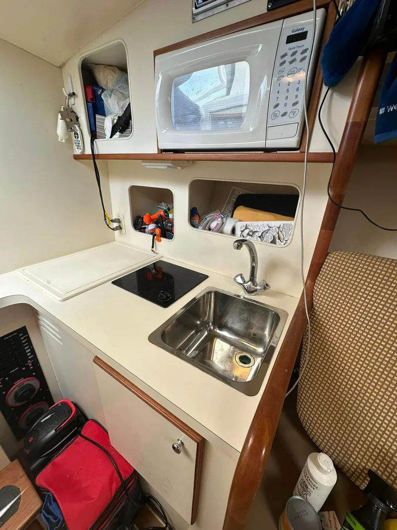 Slide: The Image of 2006 Luhrs 28 Open boat kitchen with sink, stove, and microwave. - 10