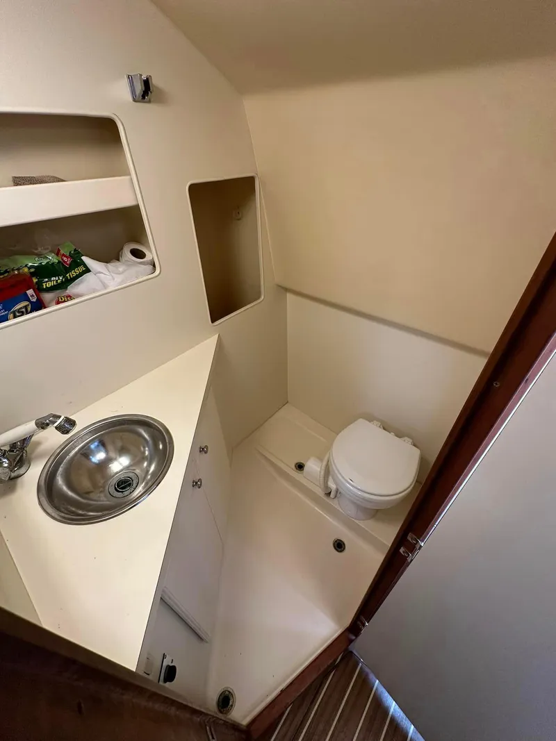Slide: The Image of 2006 Luhrs 28 Open boat bathroom with sink, toilet, and storage shelves. - 11