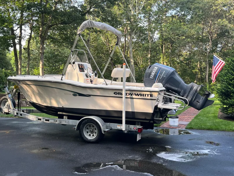 Slide: The Image of 2010 Grady-White Sportsman 180 boat on trailer, parked in driveway with American flag nearby. - 2