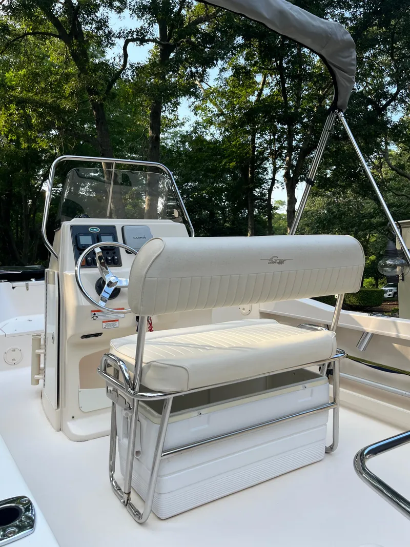 Slide: The Image of 2010 Grady-White Sportsman 180 boat interior with seating and console, set against a wooded backdrop. - 3