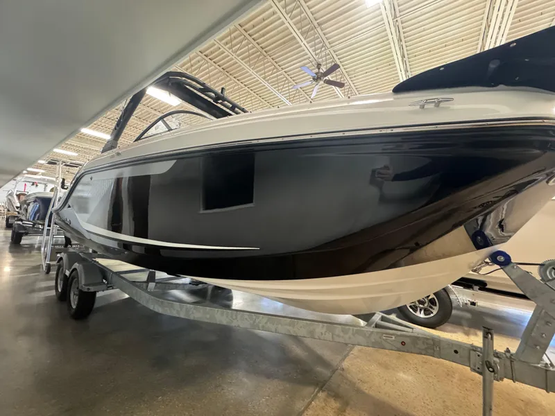 Slide: The Image of 2025 Bayliner D22 boat on trailer in showroom, sleek black and white design. - 1