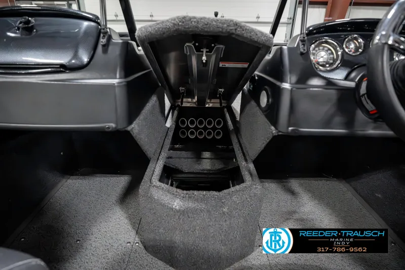 Slide: The Image of 2023 Lowe FM 1775 boat interior with open storage compartment and dashboard controls. - 24