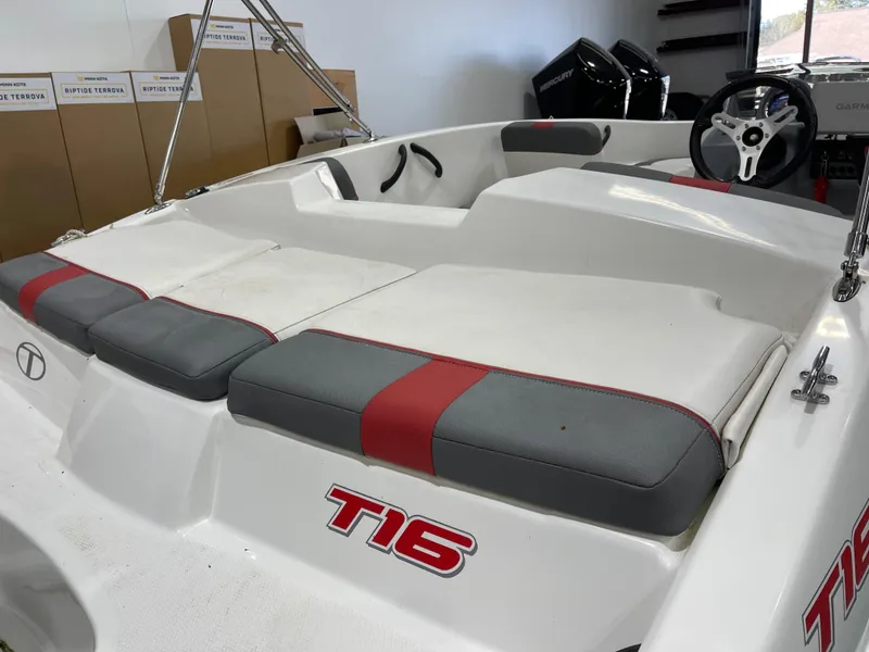 Slide: The Image of 2020 Tahoe T16 boat interior with red and gray seating, steering wheel, and storage boxes. - 22