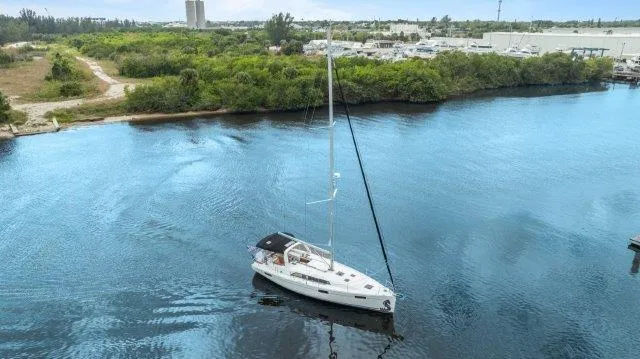 Slide: The Image of 2018 Beneteau Oceanis 41.1 sailboat on calm water near a lush shoreline. - 1