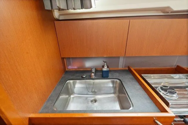Slide: The Image of Beneteau Oceanis 41.1 2018 yacht kitchen sink with wooden cabinetry and modern fixtures. - 12
