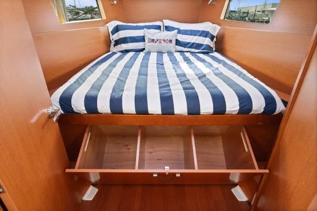 Slide: The Image of 2018 Beneteau Oceanis 41.1 cabin with striped bedding and under-bed storage. - 18