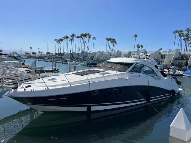 Slide: The Image of 2008 Sea Ray 55 Sundancer yacht docked in a sunny marina with palm trees. - 1