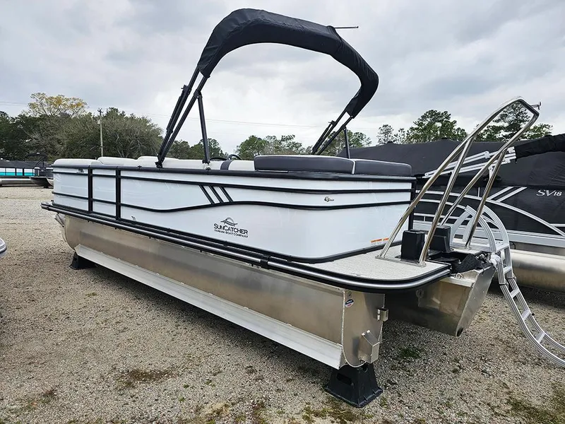 Slide: The Image of 2025 SunCatcher Select 322C pontoon boat with canopy, parked on gravel. - 4